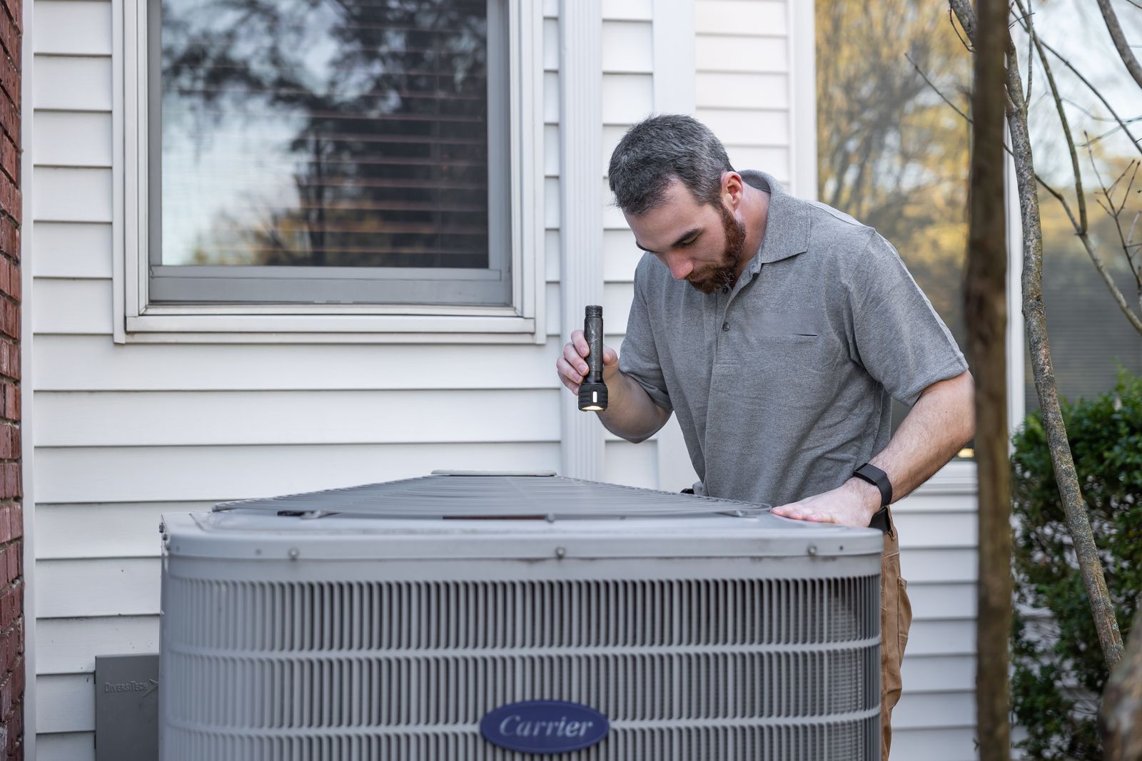 Technician inspecting a residential outdoor HVAC system
