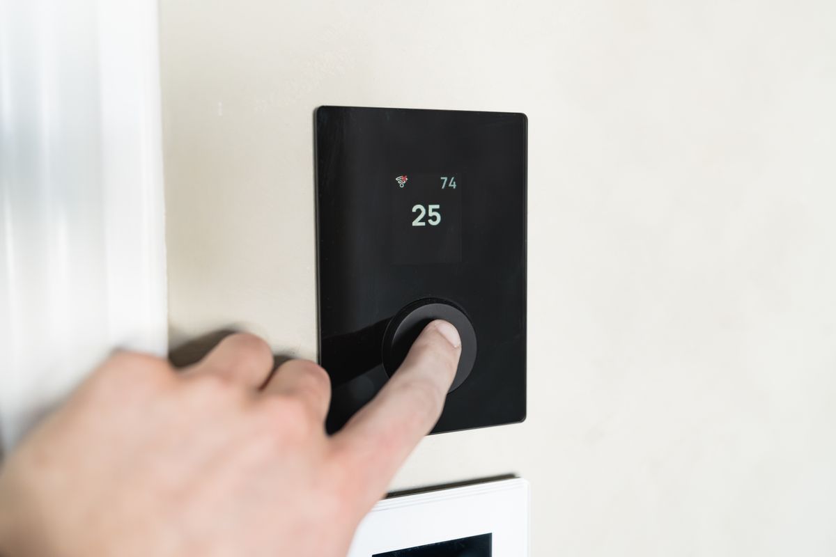 Hand adjusting a modern smart thermostat